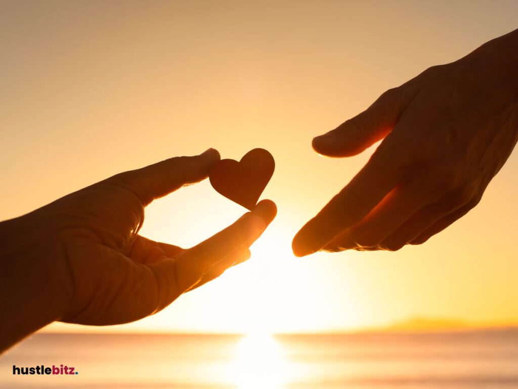a hand holding a heart and other heart preparing to receive the heart with background of sea 