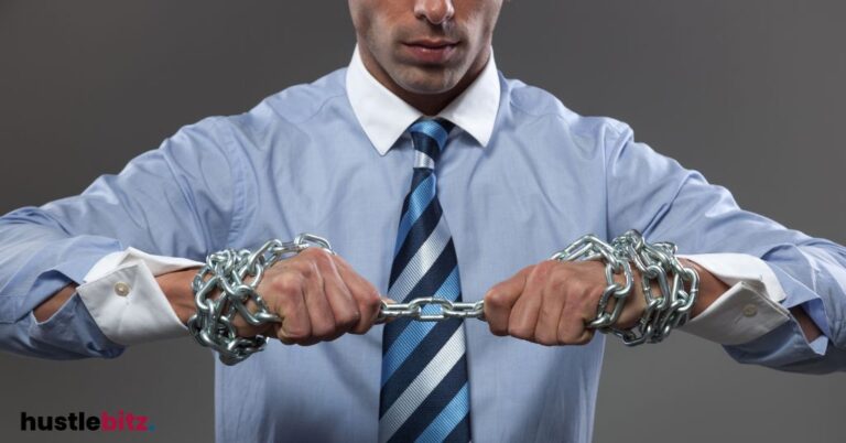 A man in a business suit breaking chains wrapped around his hands.