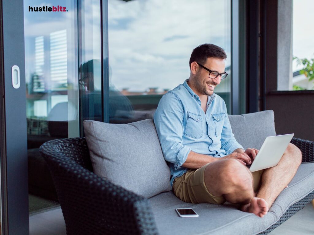 Man happily working on a laptop while sitting outdoors.