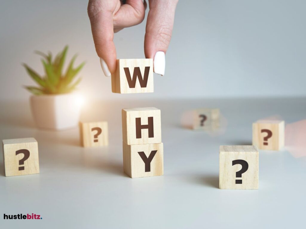 A hand placing wooden blocks spelling 'WHY,' surrounded by question marks.