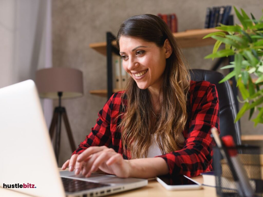 A woman smiles looking at the laptop