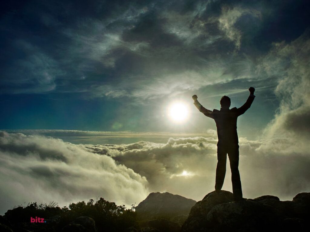 A man triumphs on a mountain, symbolizing overcoming fear and personal growth.
