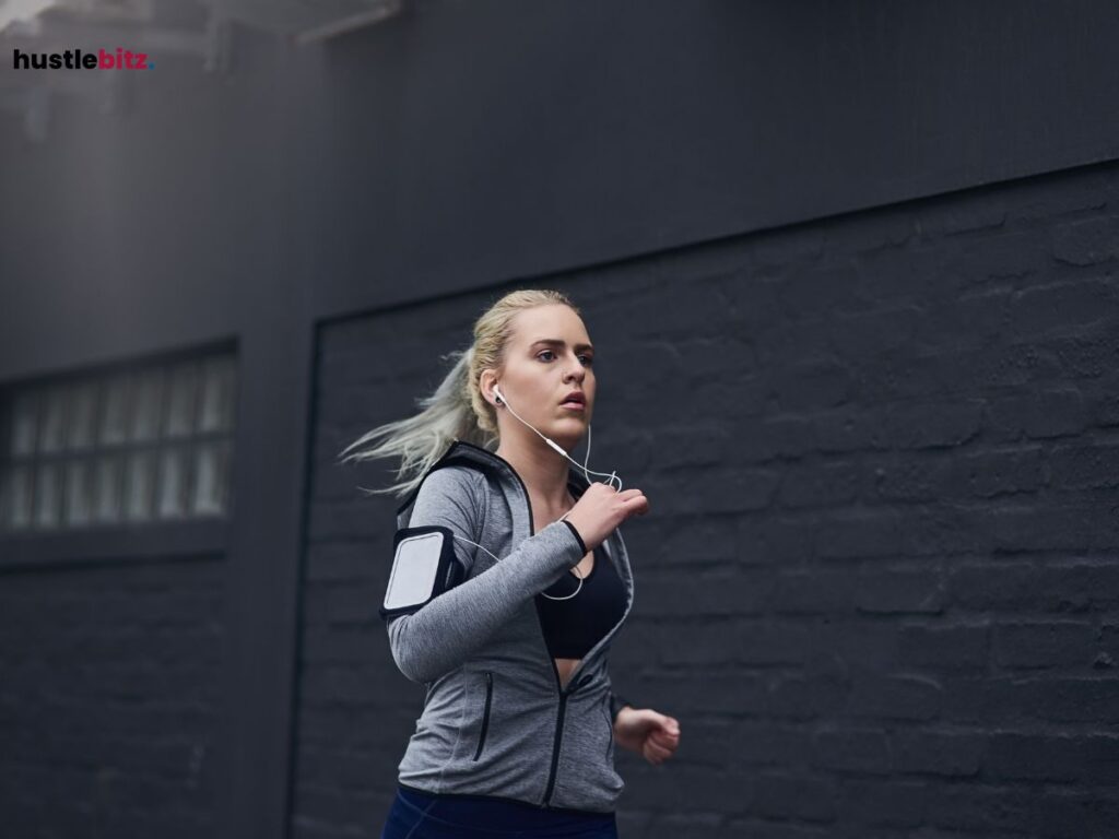 A woman jogging outdoors, focused and listening to music through earphones.