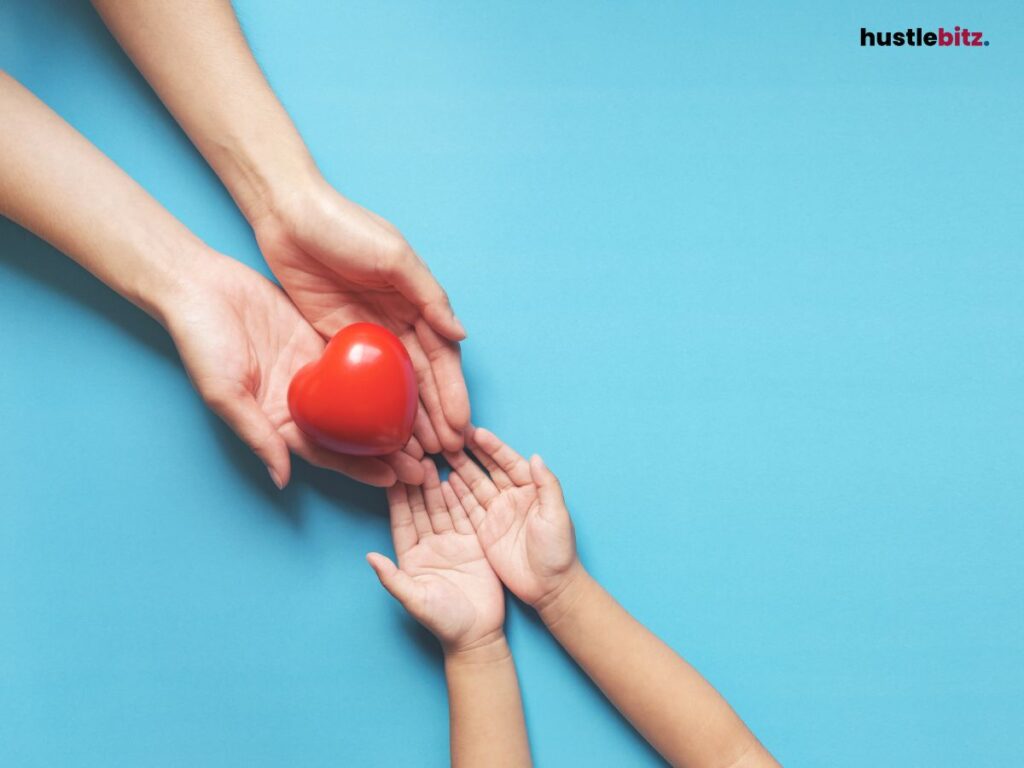 Hands passing a red heart to a child on a blue background.