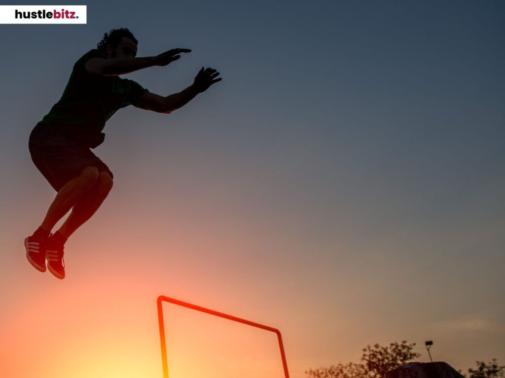 Silhouette of a man jumping over an obstacle at sunset.