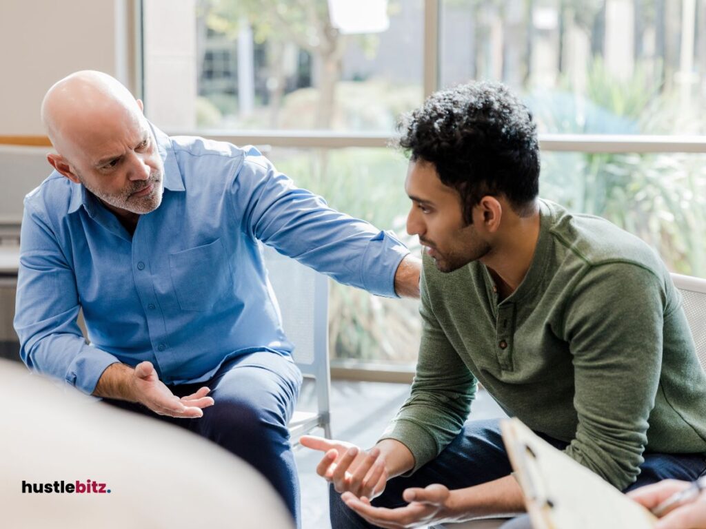 The image shows an older man offering support to a younger man.