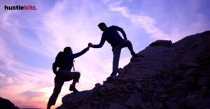 Two people helping each other climbing the mountain with a cloudy background