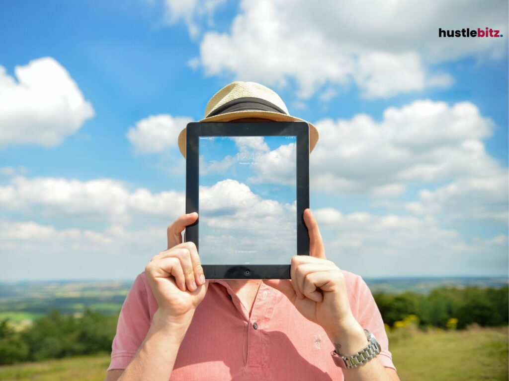 A person holding a tablet with a sky reflection covering their face.