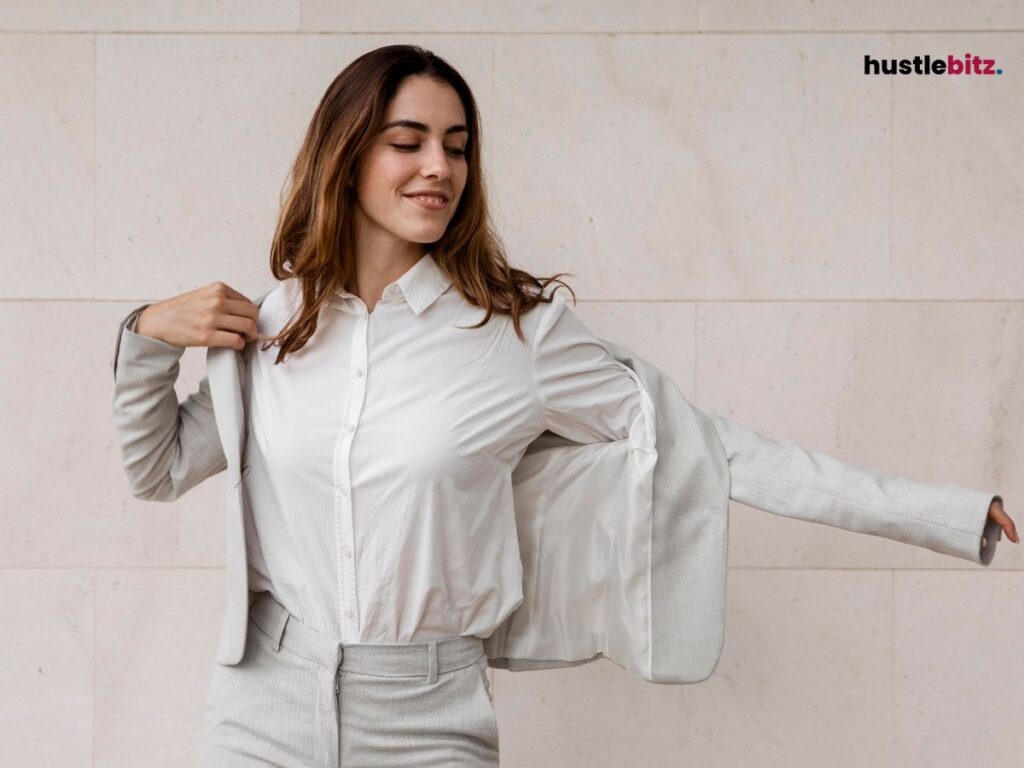 A woman putting her blazer on and smiling.