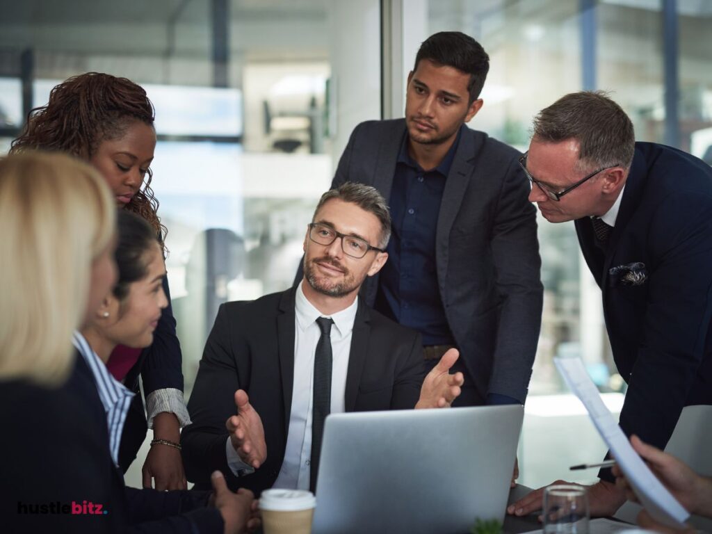 Group of people looking at the man sitting and wearing eyeglass