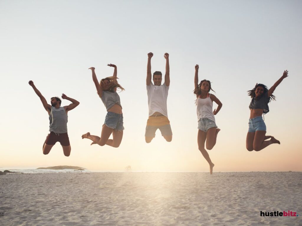 Five friends jumping on the beach at sunset.