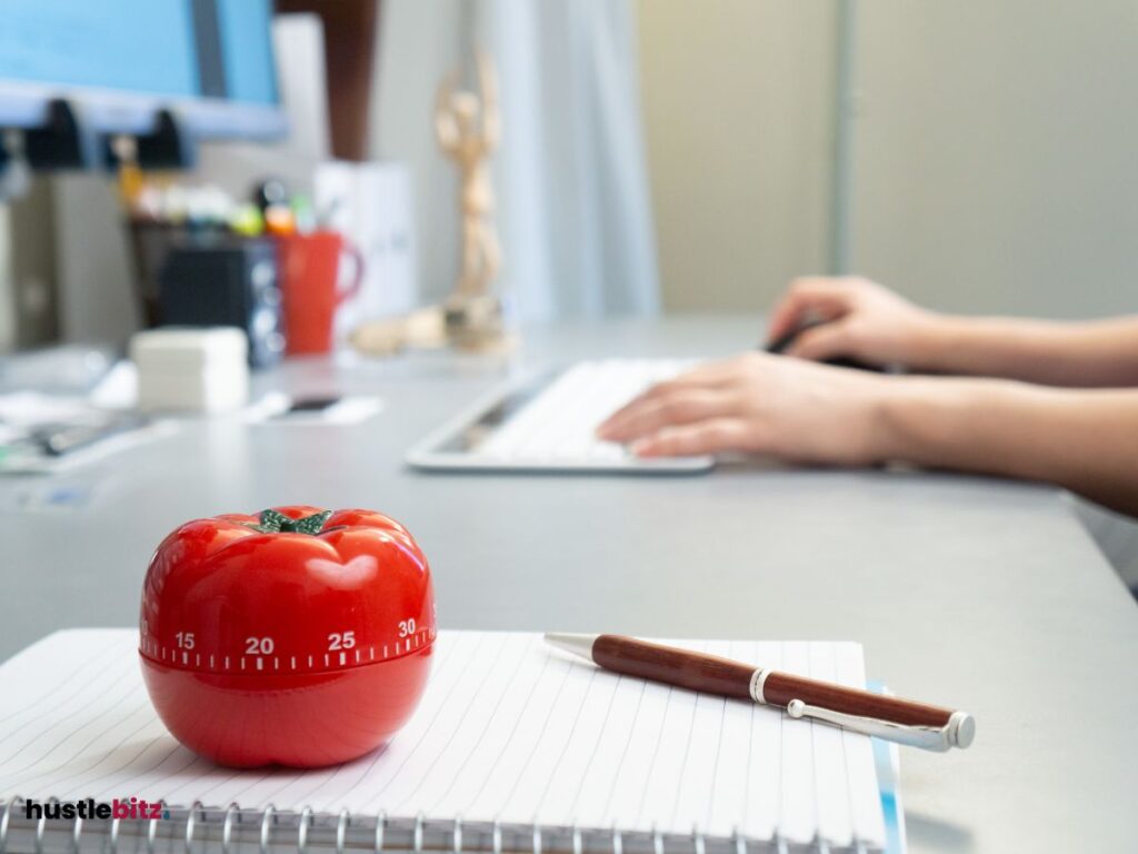 A Pomodoro above the paper with pen and a hand background