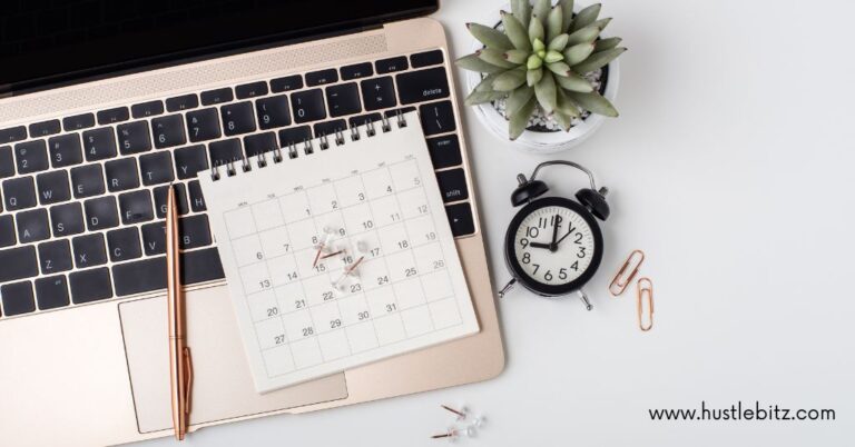 A laptop with a calendar, clock, and pen on a desk, next to a plant.