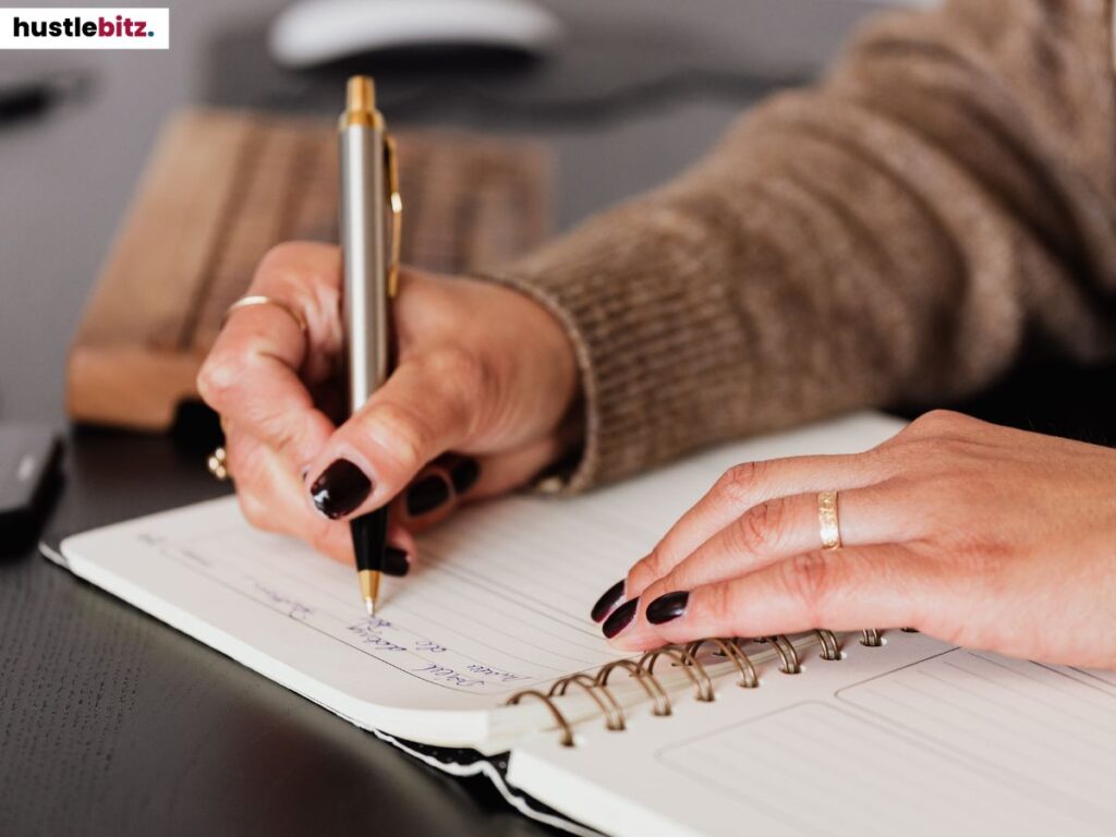 Handwriting in a journal, focusing on the hand holding a pen.