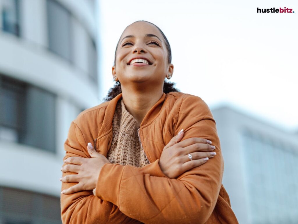A woman in brown coat embracing herself.