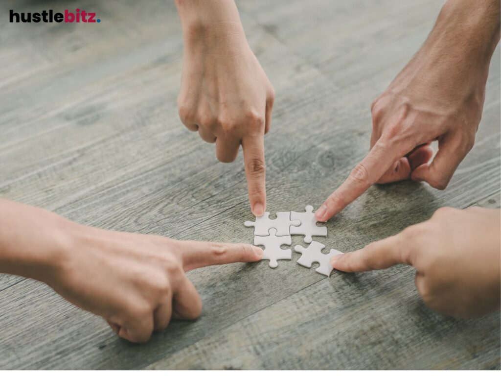 Four hands putting puzzle pieces together on a table.