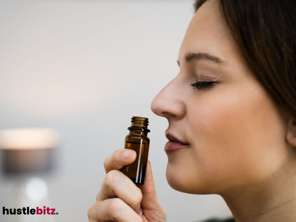 A woman enjoying the scent of an essential oil from a small brown bottle.