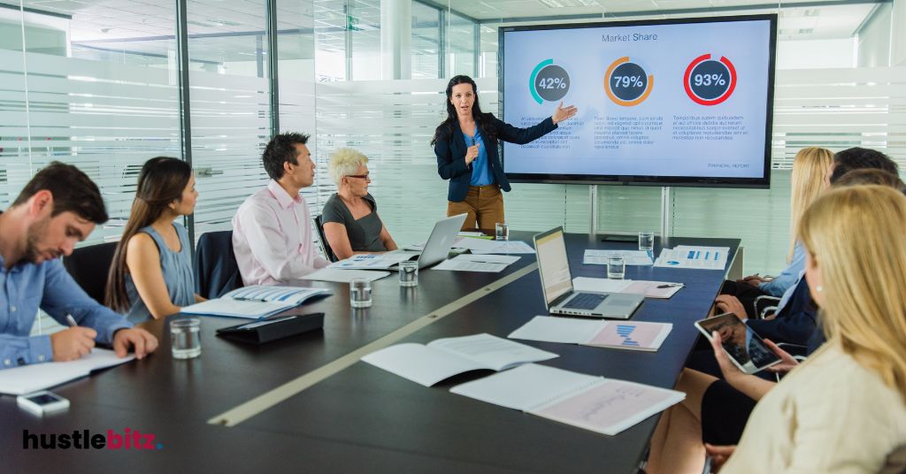 A woman presenting market share data to a team in a modern conference room.