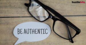 Glasses with "Be Authentic" speech bubble on wood surface.