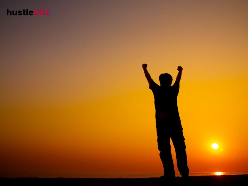 Silhouette of a person raising arms at sunrise, celebrating a personal victory.