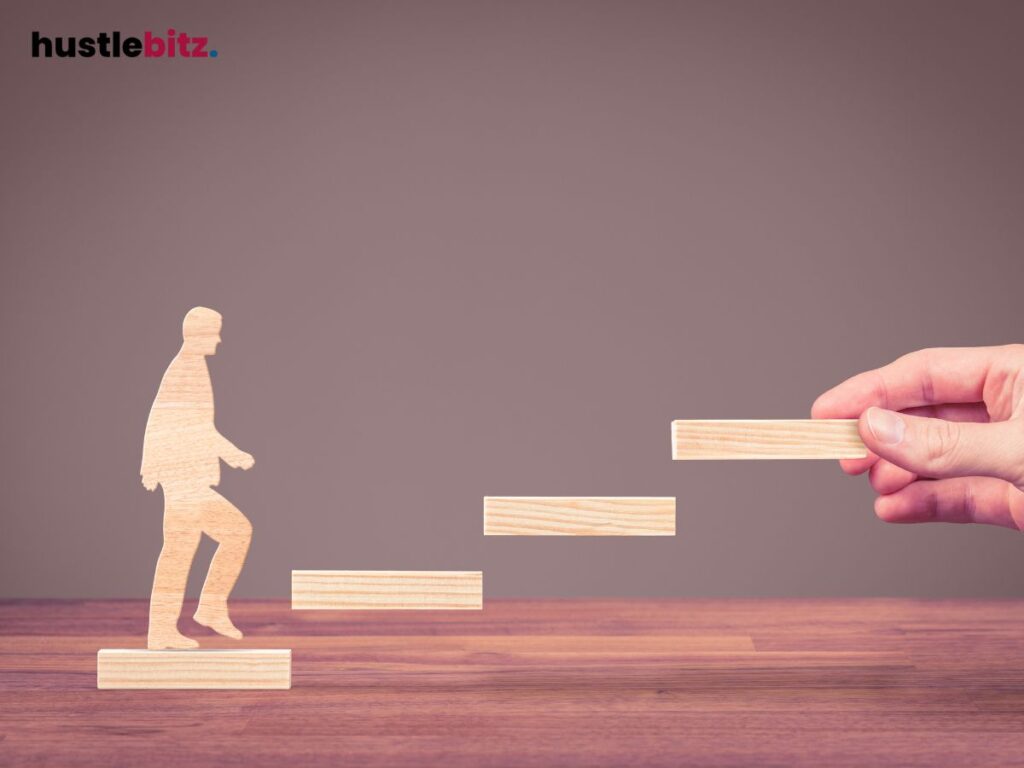 A hand helps a wooden figure ascend steps, symbolizing personal growth.