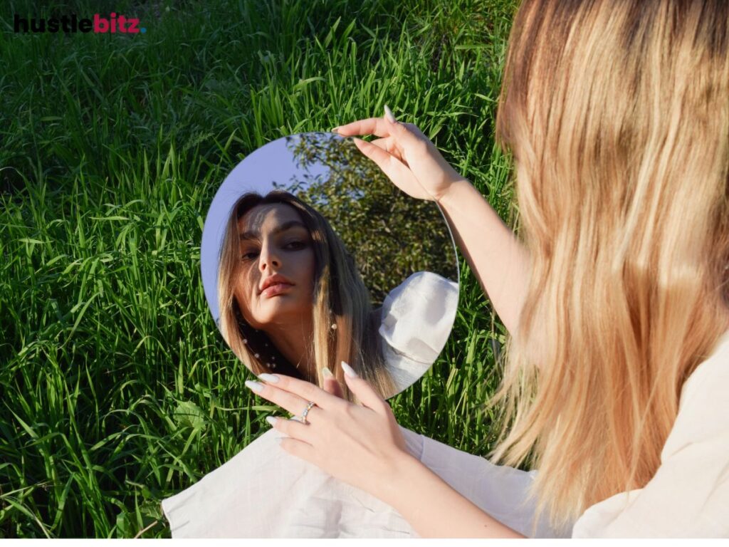 Woman holding a mirror in a field, symbolizing self-reflection and identity.