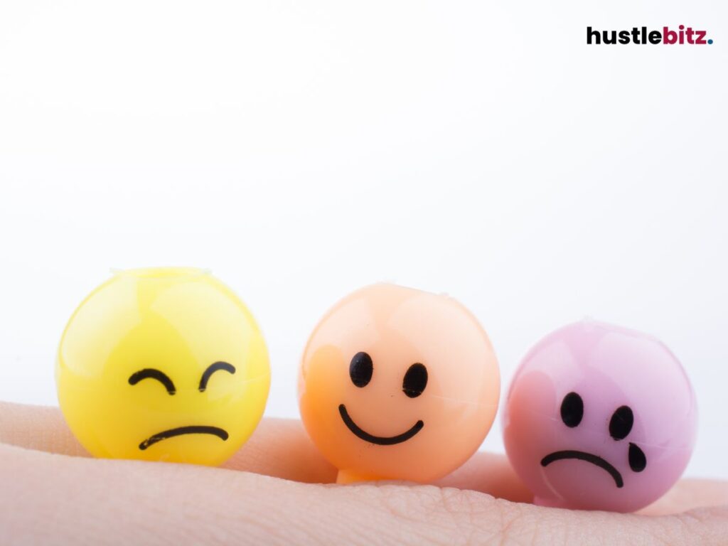 Three small smiley face balls with different emotions on a finger.