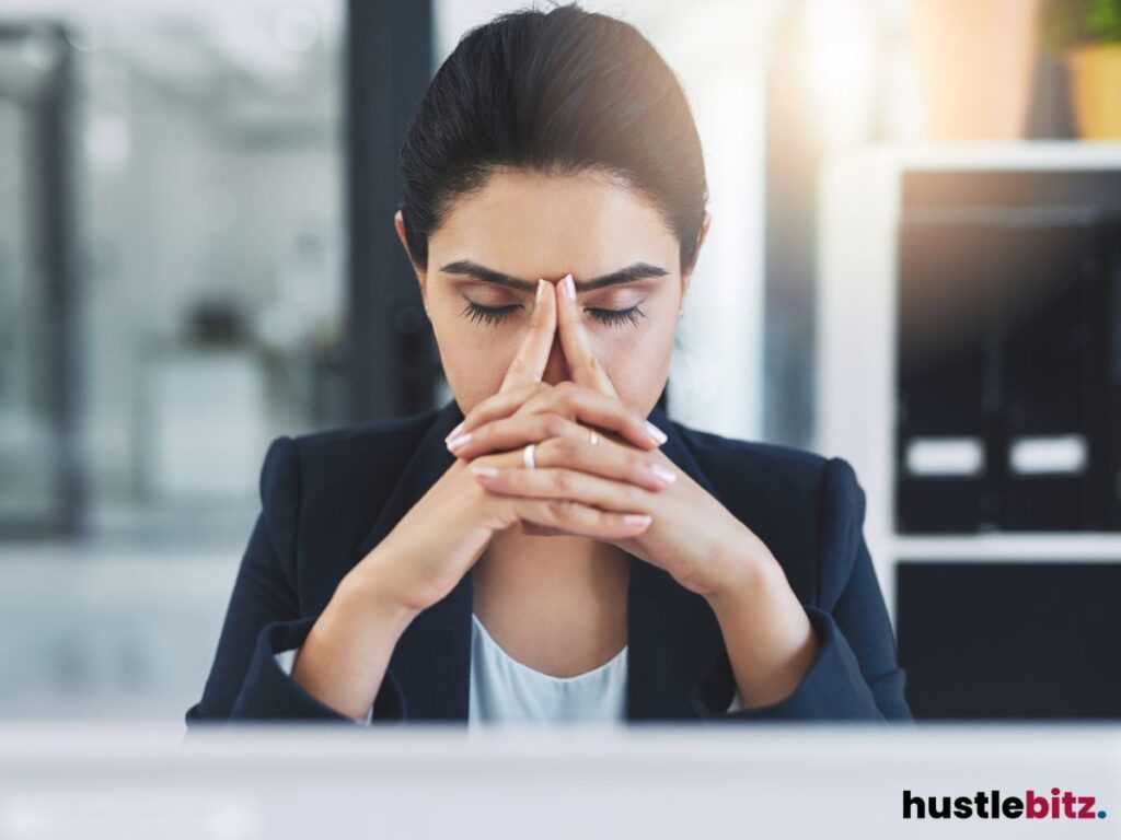 A woman closing her eyes and putting her hands in front of her face.