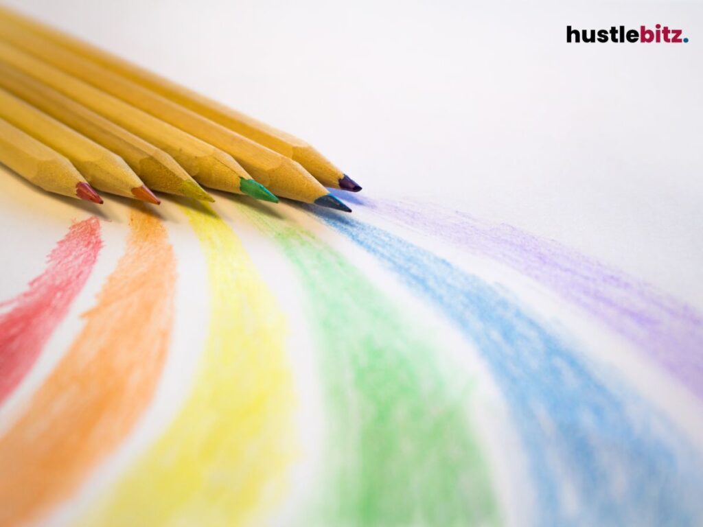 Colored pencils drawing rainbow lines on white paper.