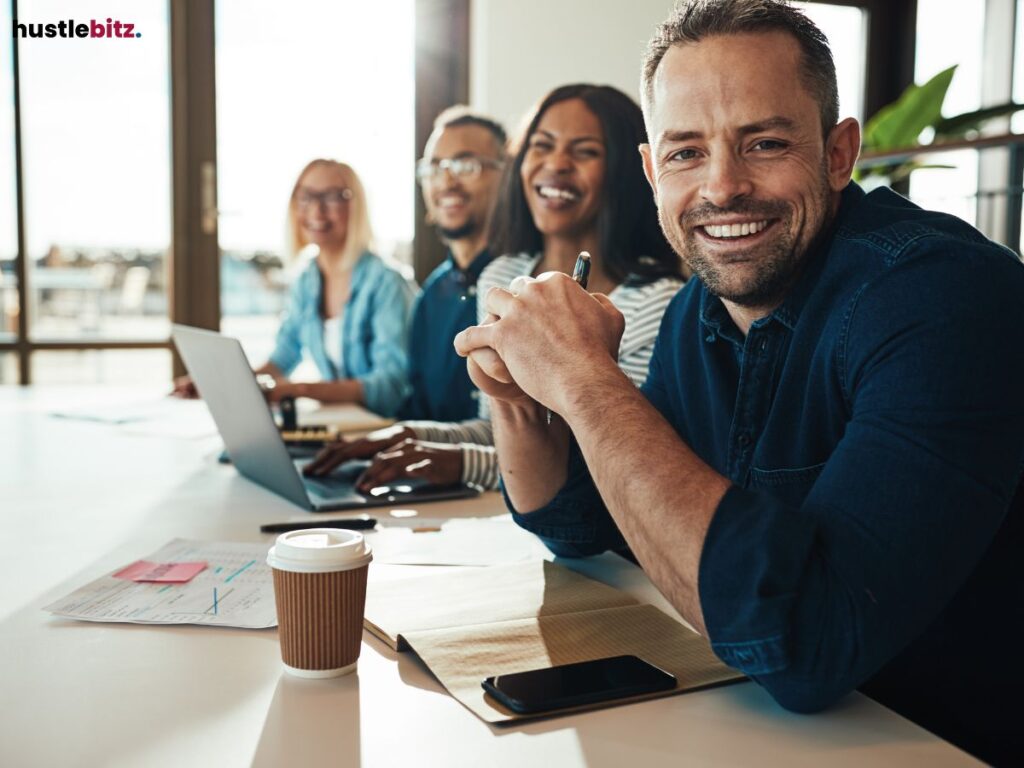 A group of people in the office smiles while looking at the camera