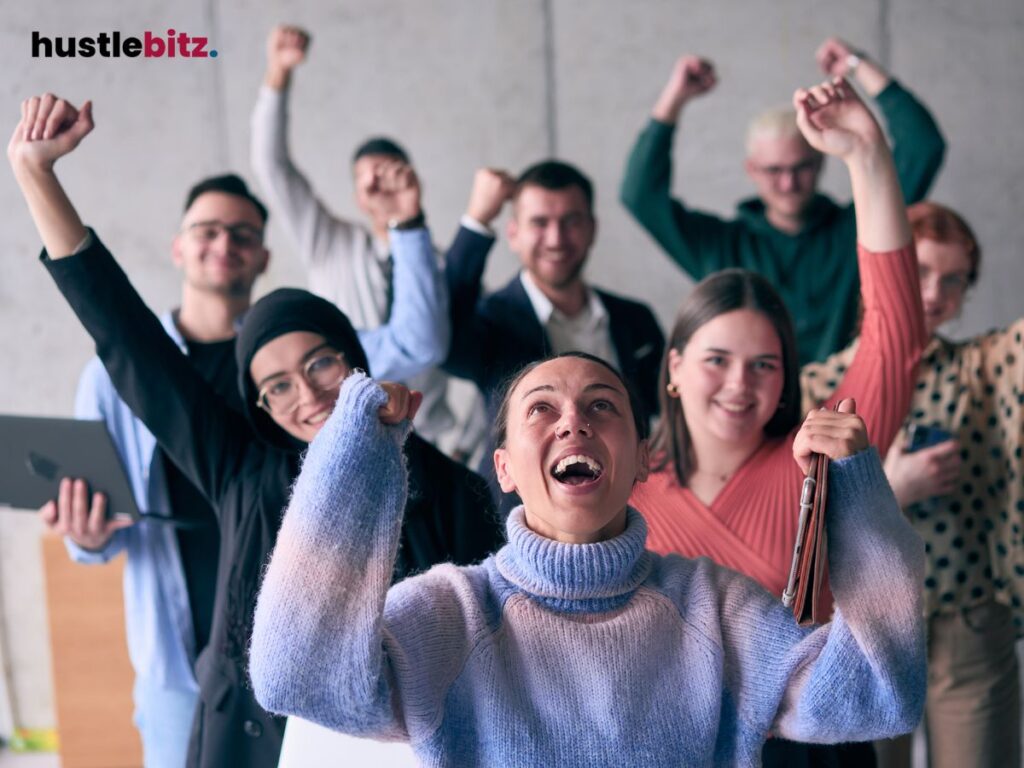 A group of people raise their hands and smiles