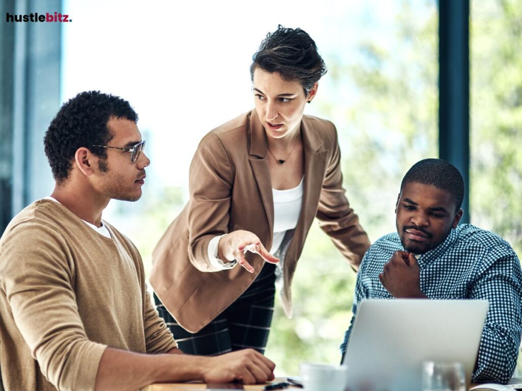  A woman discussing strategy with two male colleagues in an office setting.