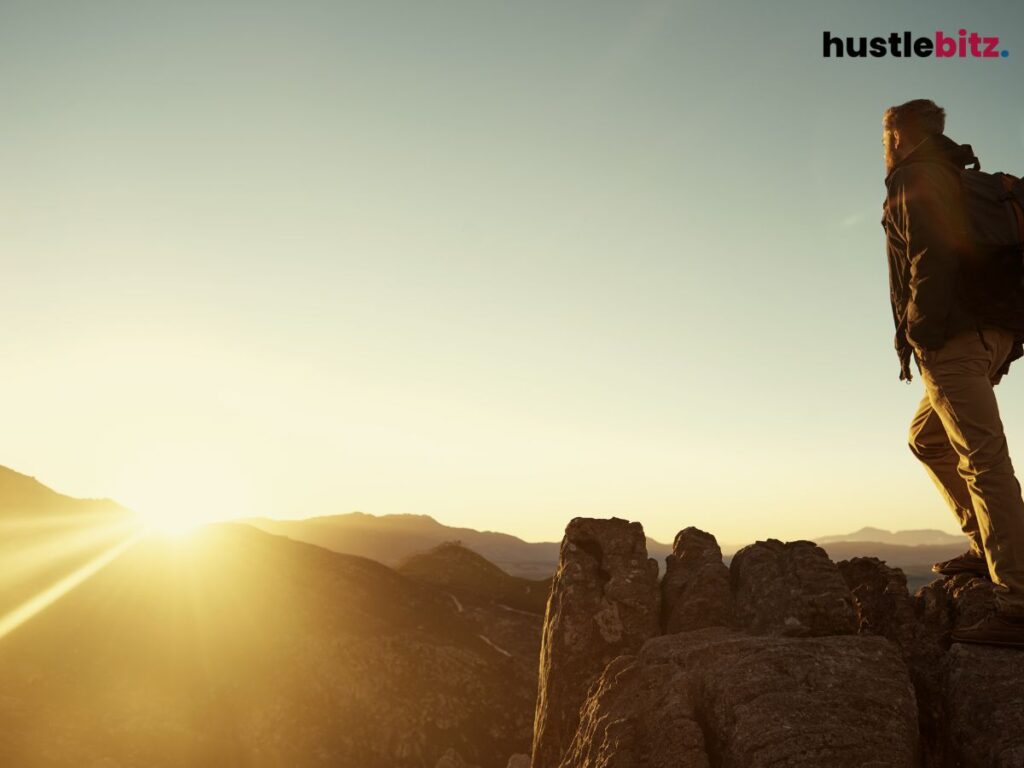 A person beside the cliff looking at the sunset
