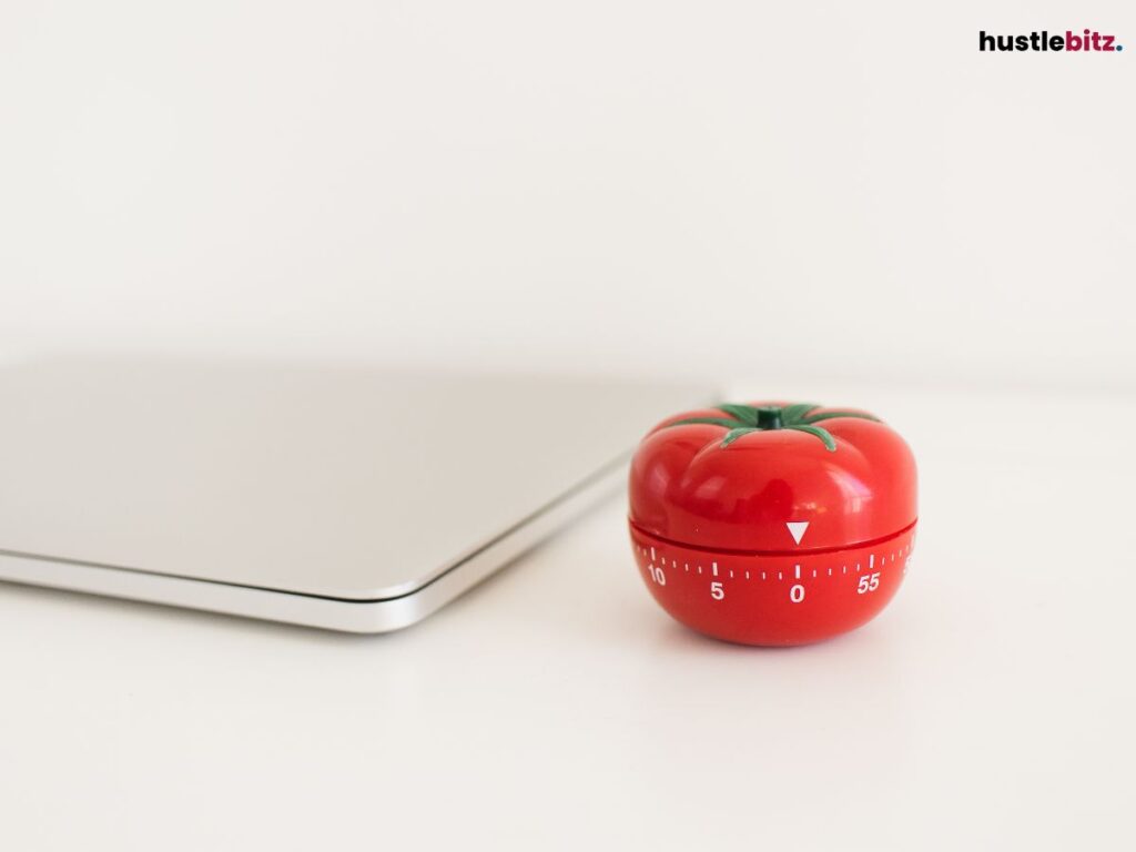 A tomato shape timer beside a laptop.