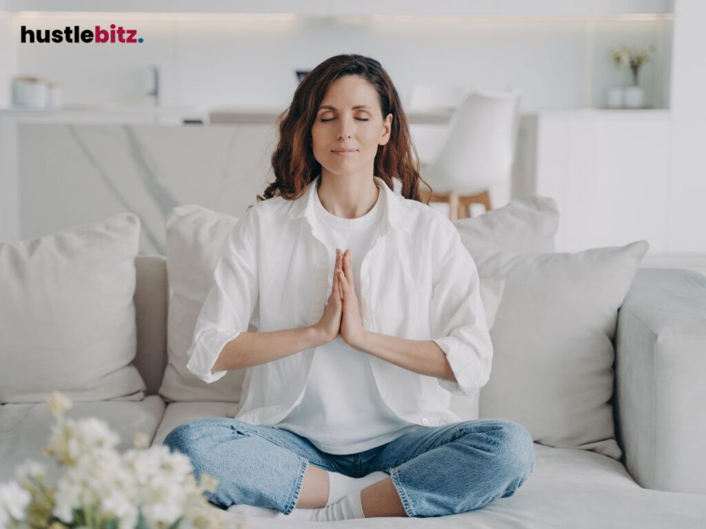 A woman meditating on a couch.