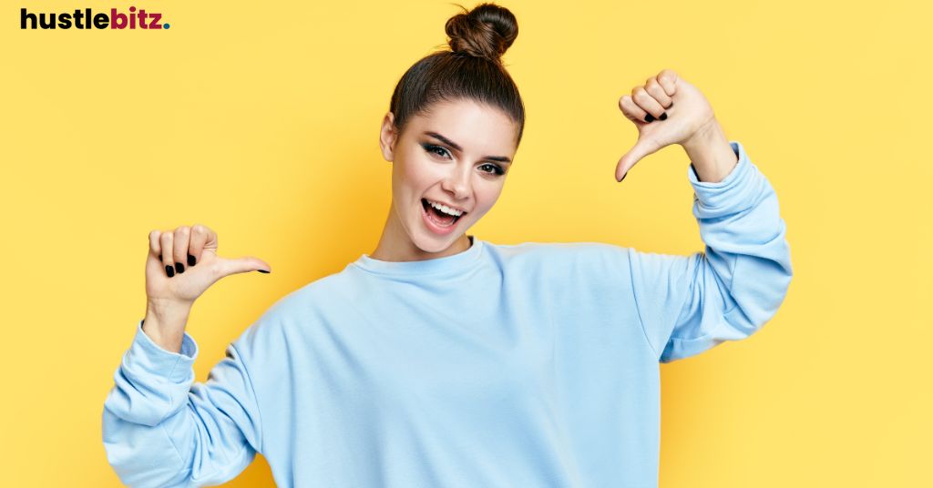 A woman smiles in front of the camera while pointing at herself