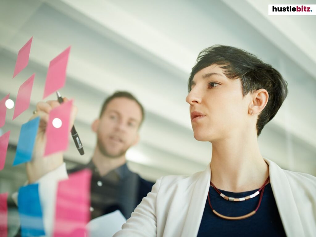 A woman writes ideas on sticky notes while discussing with a colleague.