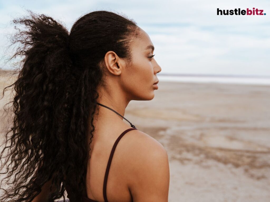 Woman with curly hair gazing off into the distance at the beach.