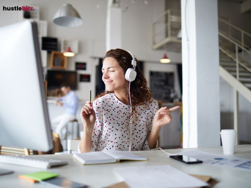 Person joyfully singing while writing at a bright desk in a modern workspace.