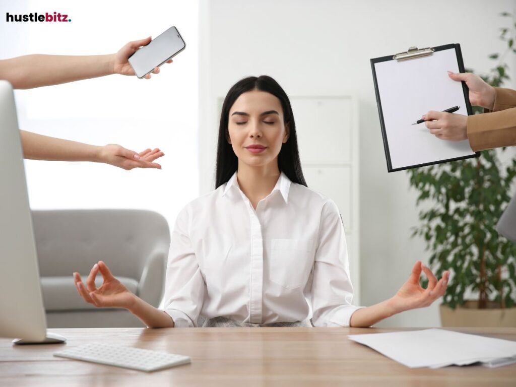 A woman in a white shirt meditating peacefully at her desk
