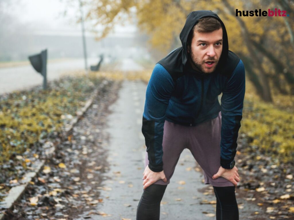 A man holding his breath and holding his knee beside the road
