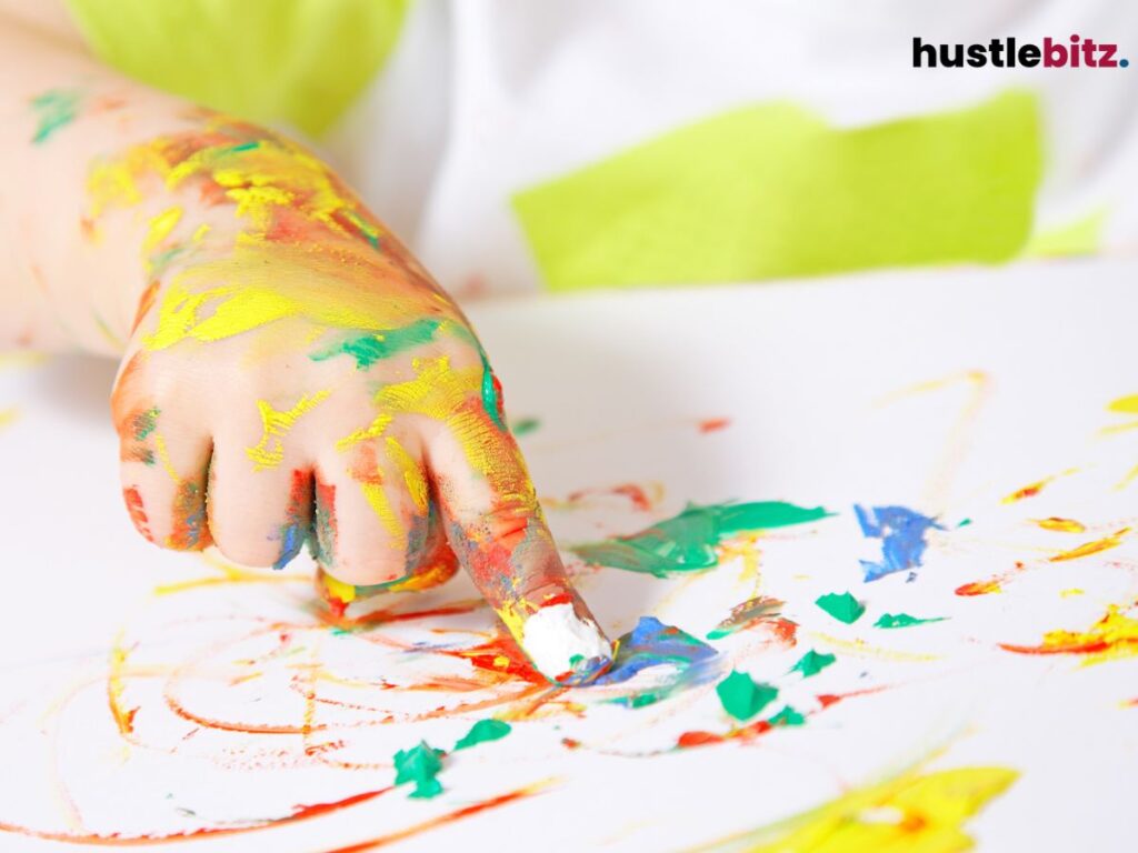 A hand covered in colorful paint, finger-painting on a surface.