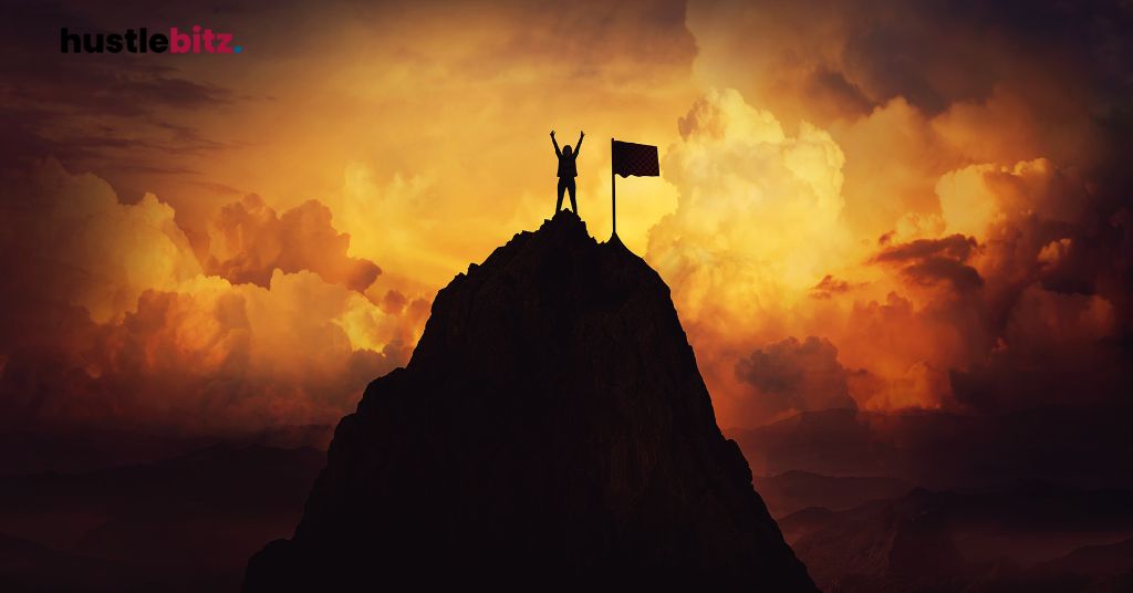 A person triumphantly stands atop a mountain with a flag, celebrating victory.