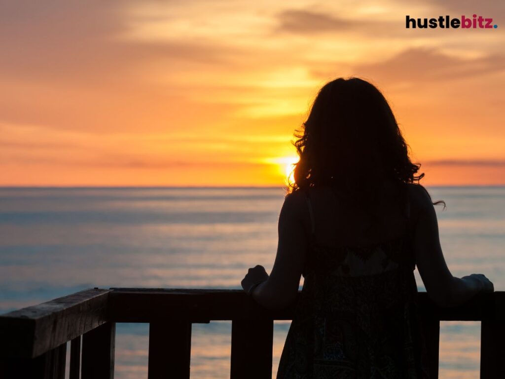 A woman beside the sea looking the at sunset