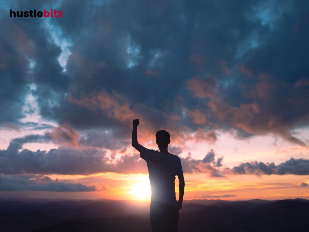 A silhouette of a person raising a fist triumphantly at sunset.