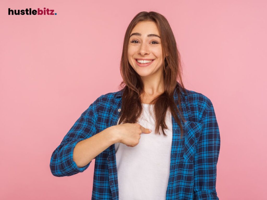 A woman smiling while pointing herself