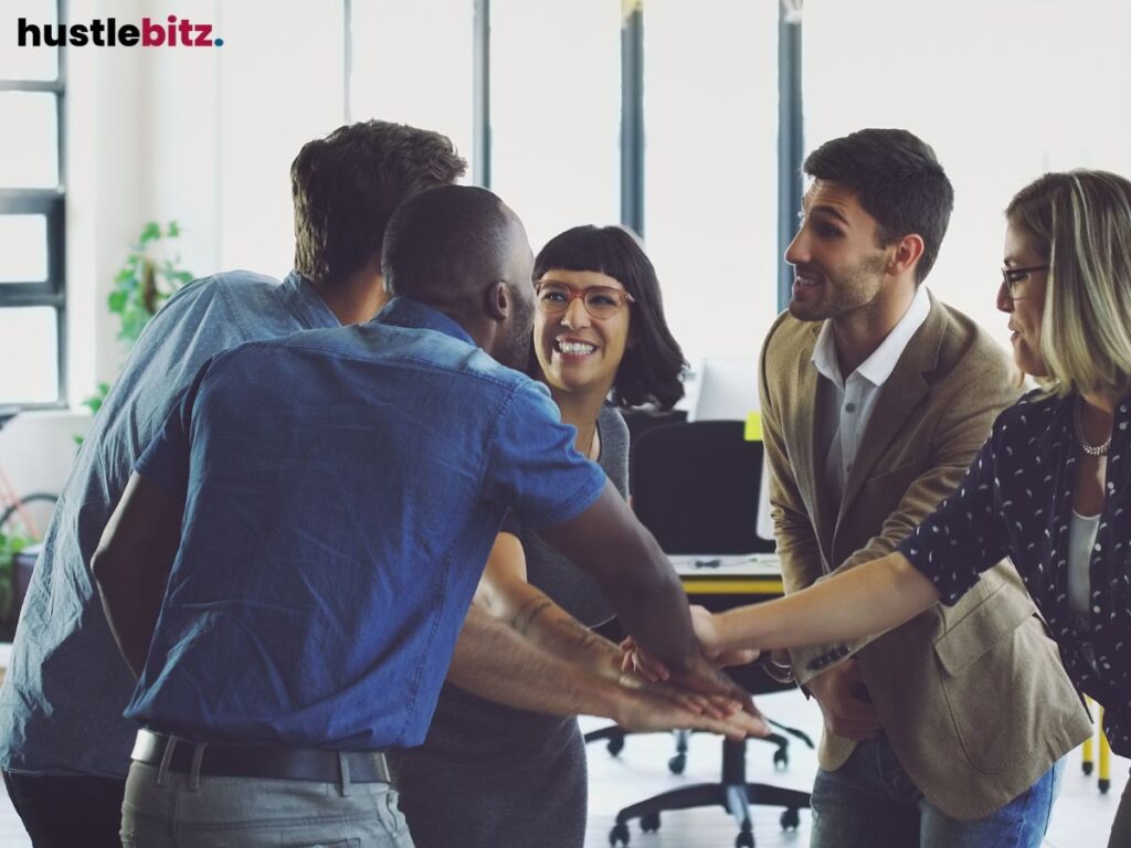 A group of people looking each other and tap their hands together inside the office