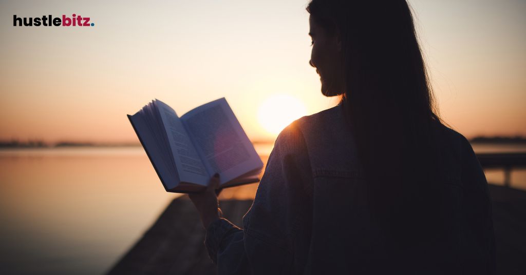 A woman reading books beside the lake