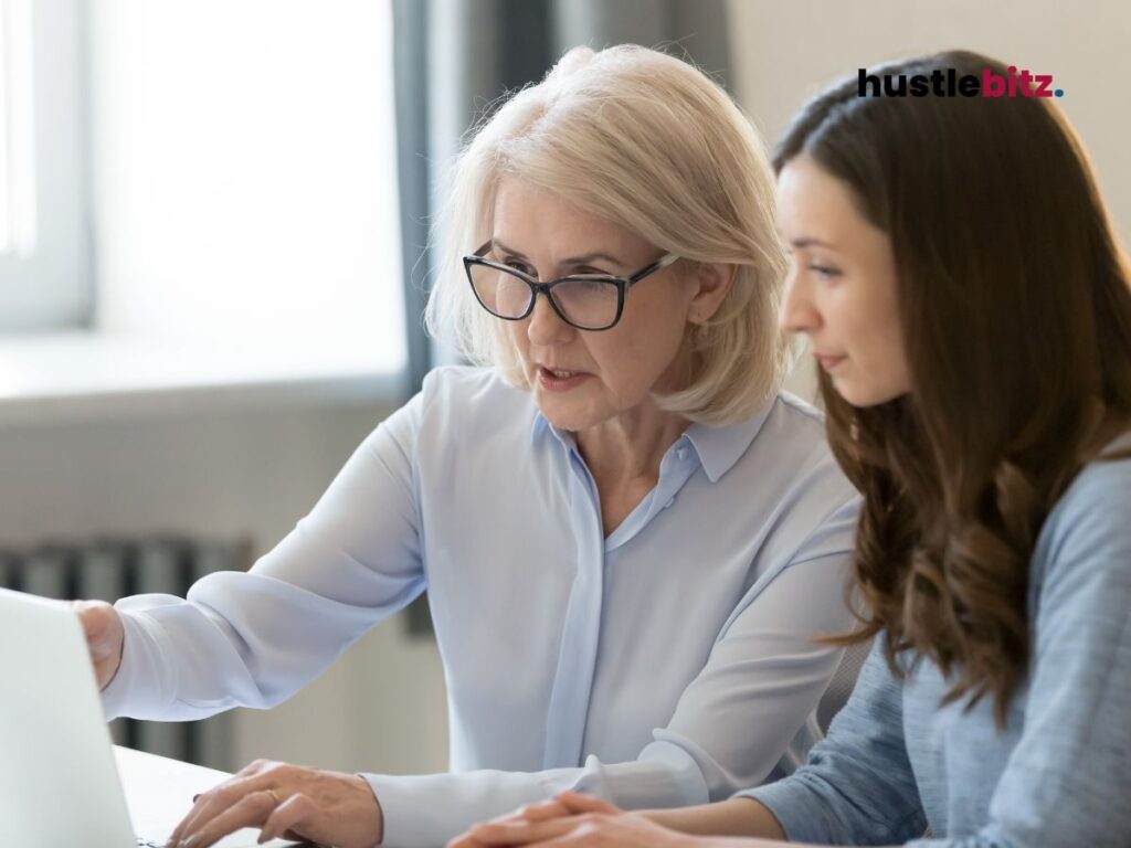 Old woman wearing eyeglass teaching the young woman inside the office