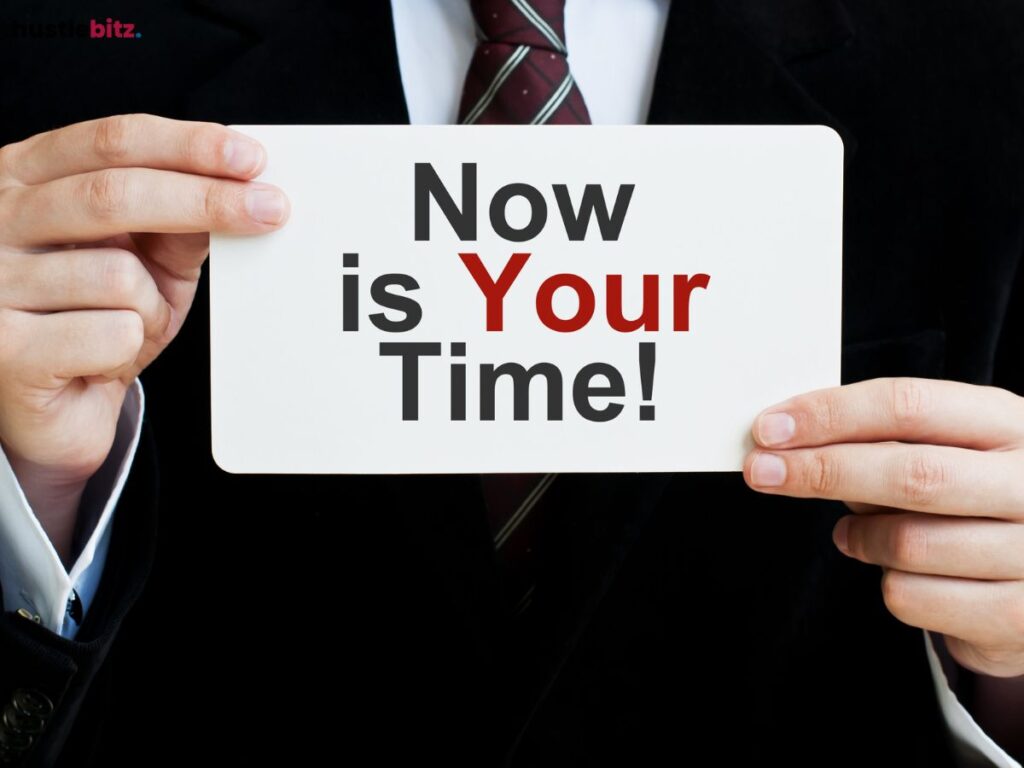 Hands holding a sign that reads "Now is Your Time" in bold black and red text.